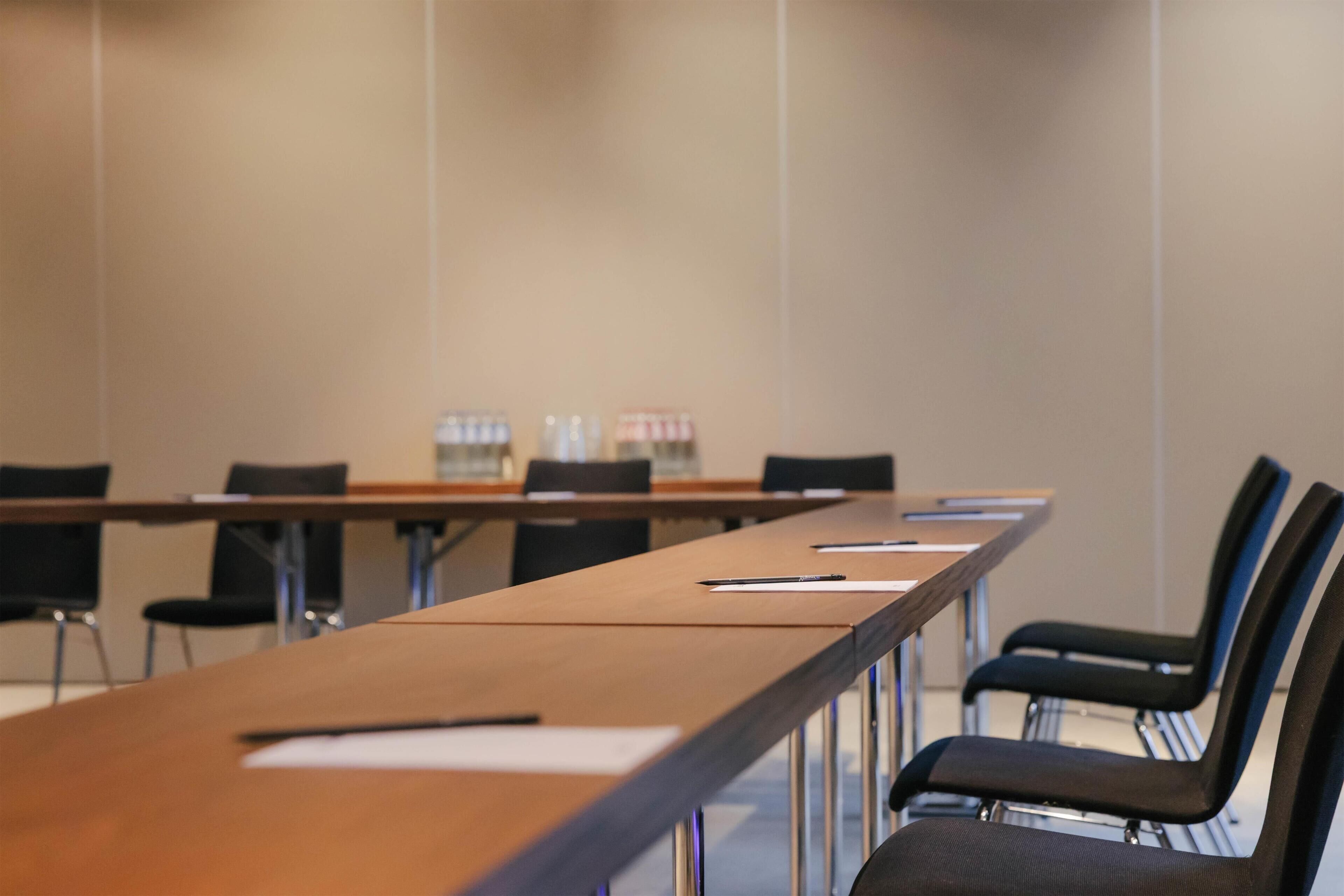 A conference room with a long table, black chairs, and water bottles on the table.