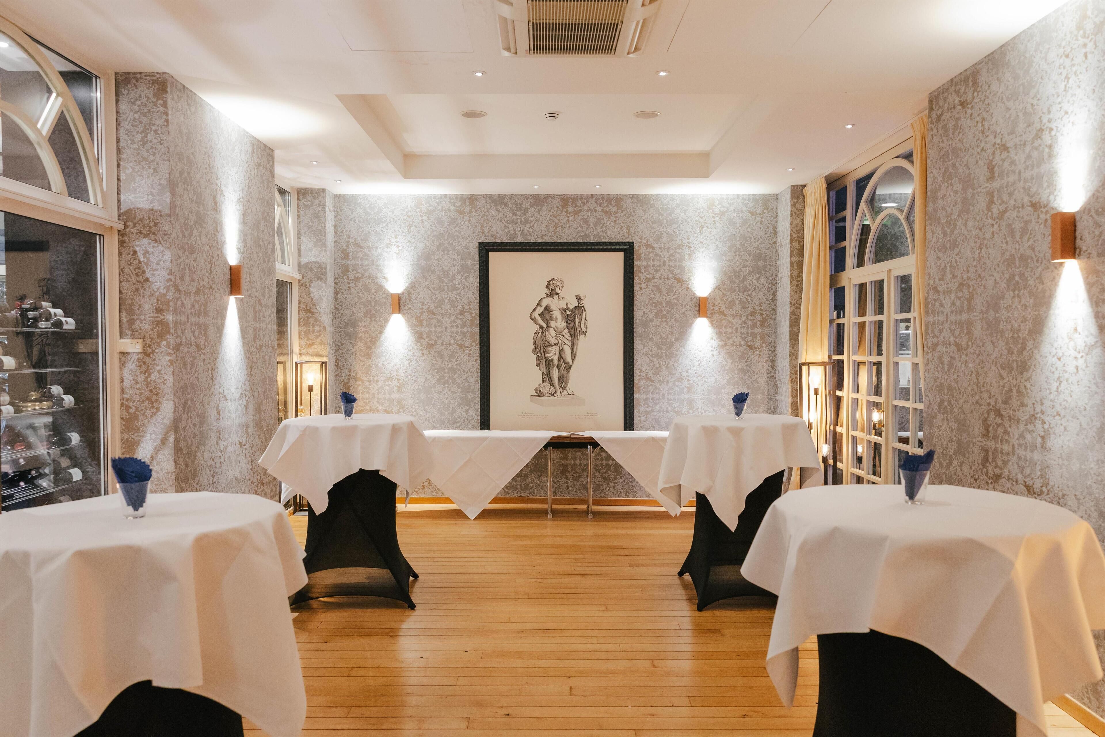 A dining area with two tables, marble walls, and framed artwork.