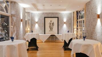 A dining area with two tables, marble walls, and framed artwork.