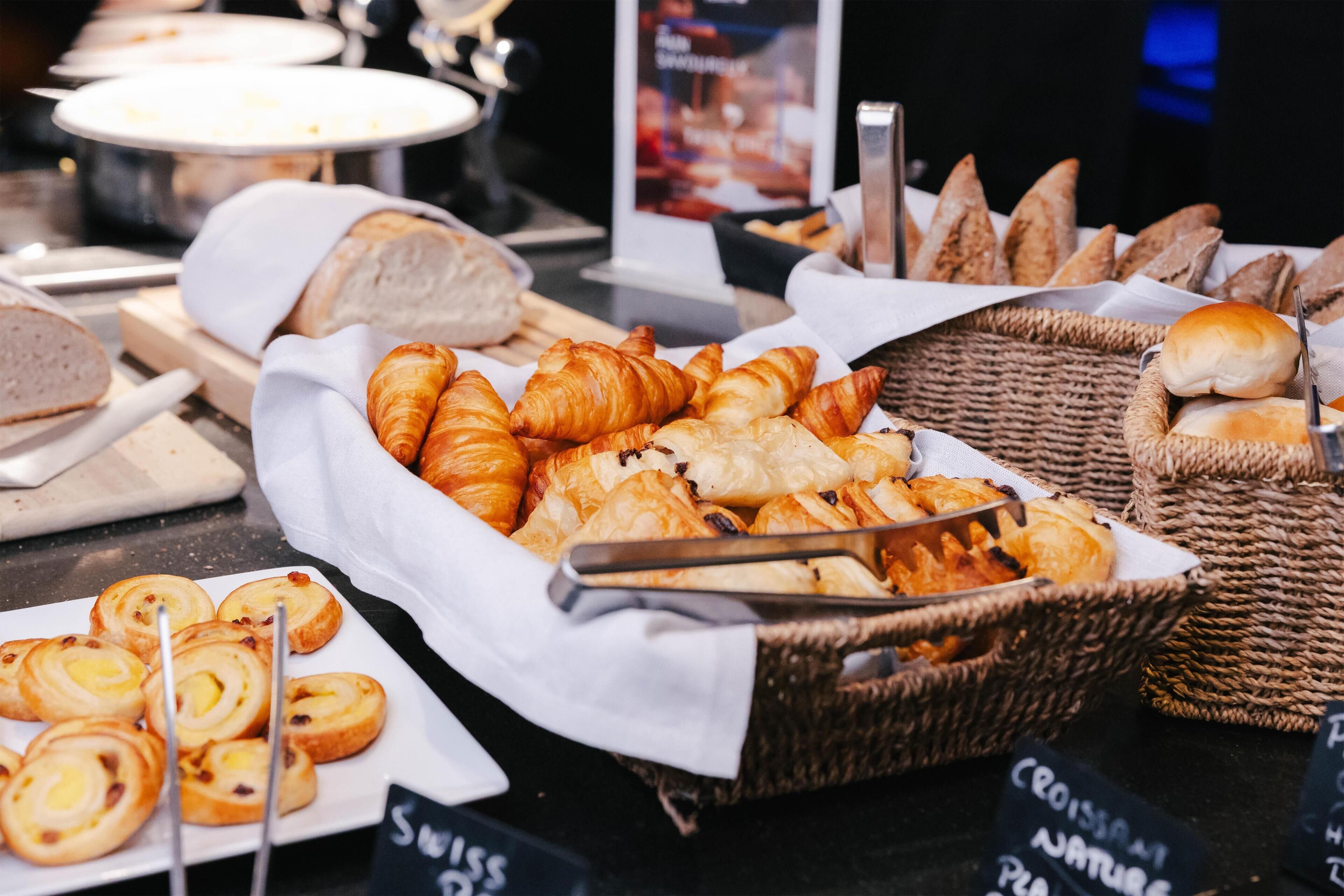 Une variété de produits de boulangerie, notamment des croissants, du pain et des pâtisseries, sont exposés sur un comptoir.