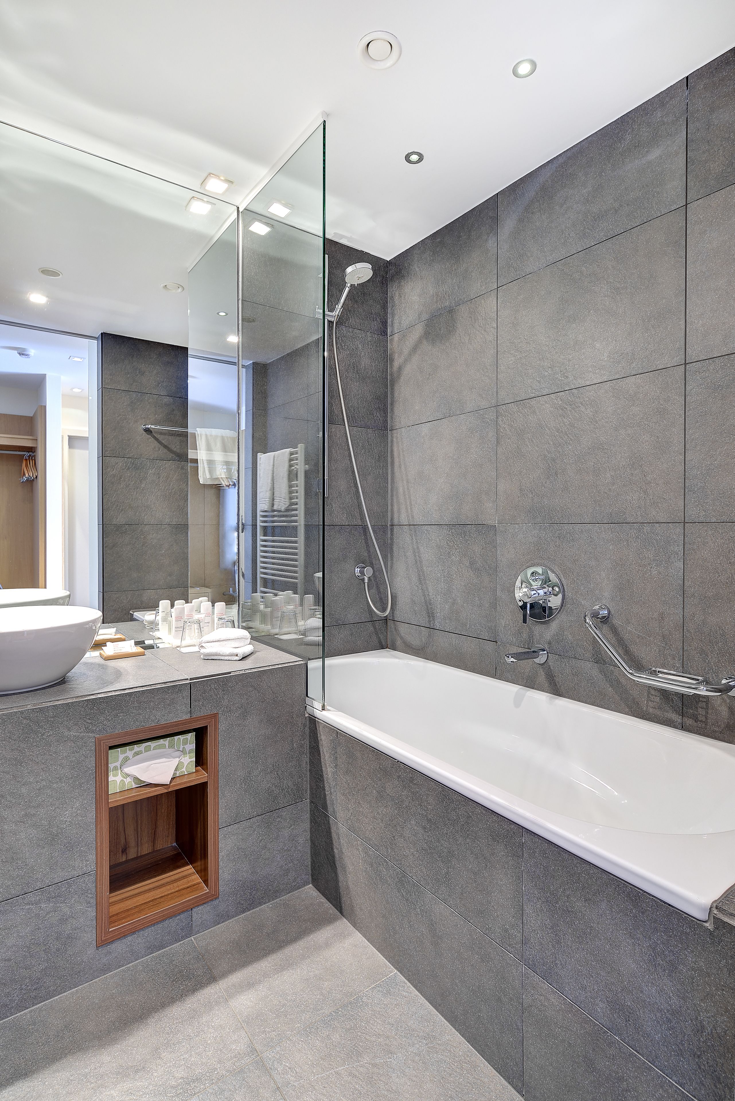Een moderne badkamer met een ruime badkuip, een douche met glazen wanden en een wastafel met grote spiegel.