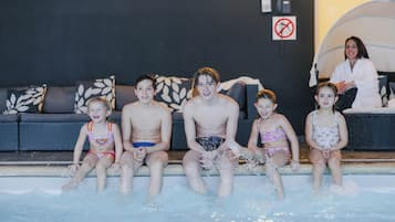 A family of five sitting by a pool with a sofa and a no-smoking sign in the background.