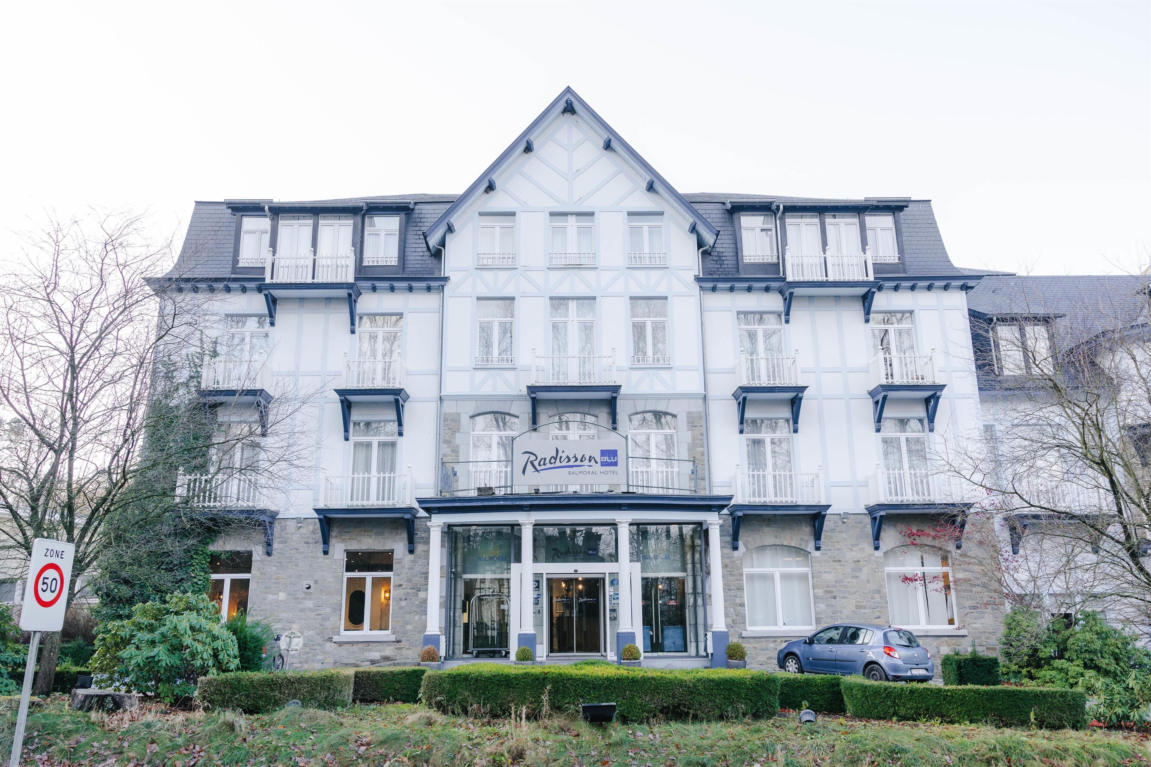 A large, multi-story hotel with a classic architectural style, featuring a prominent entrance and a signboard.