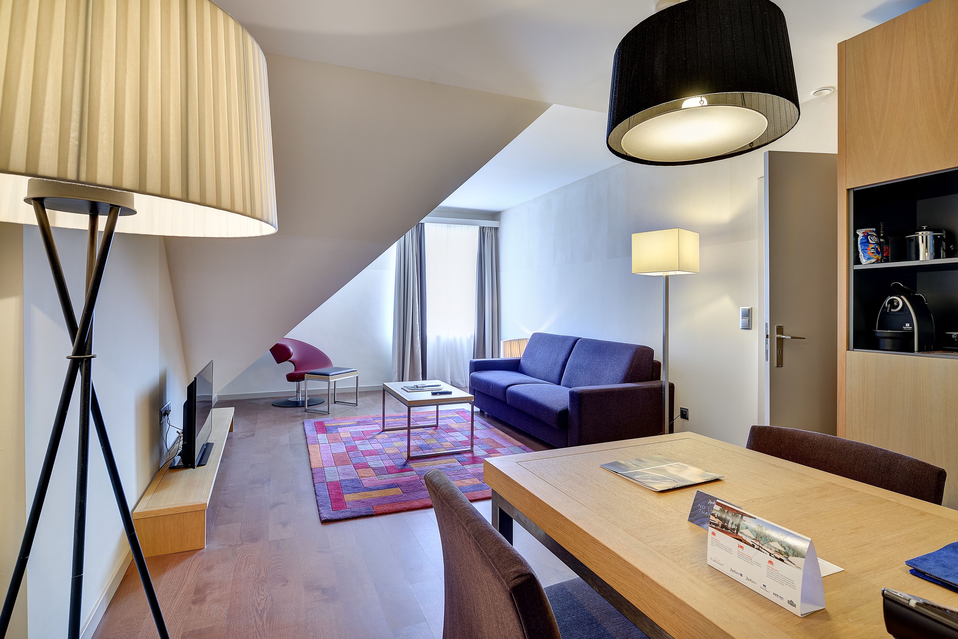 A modern living room with a sofa, a dining table, and a TV.