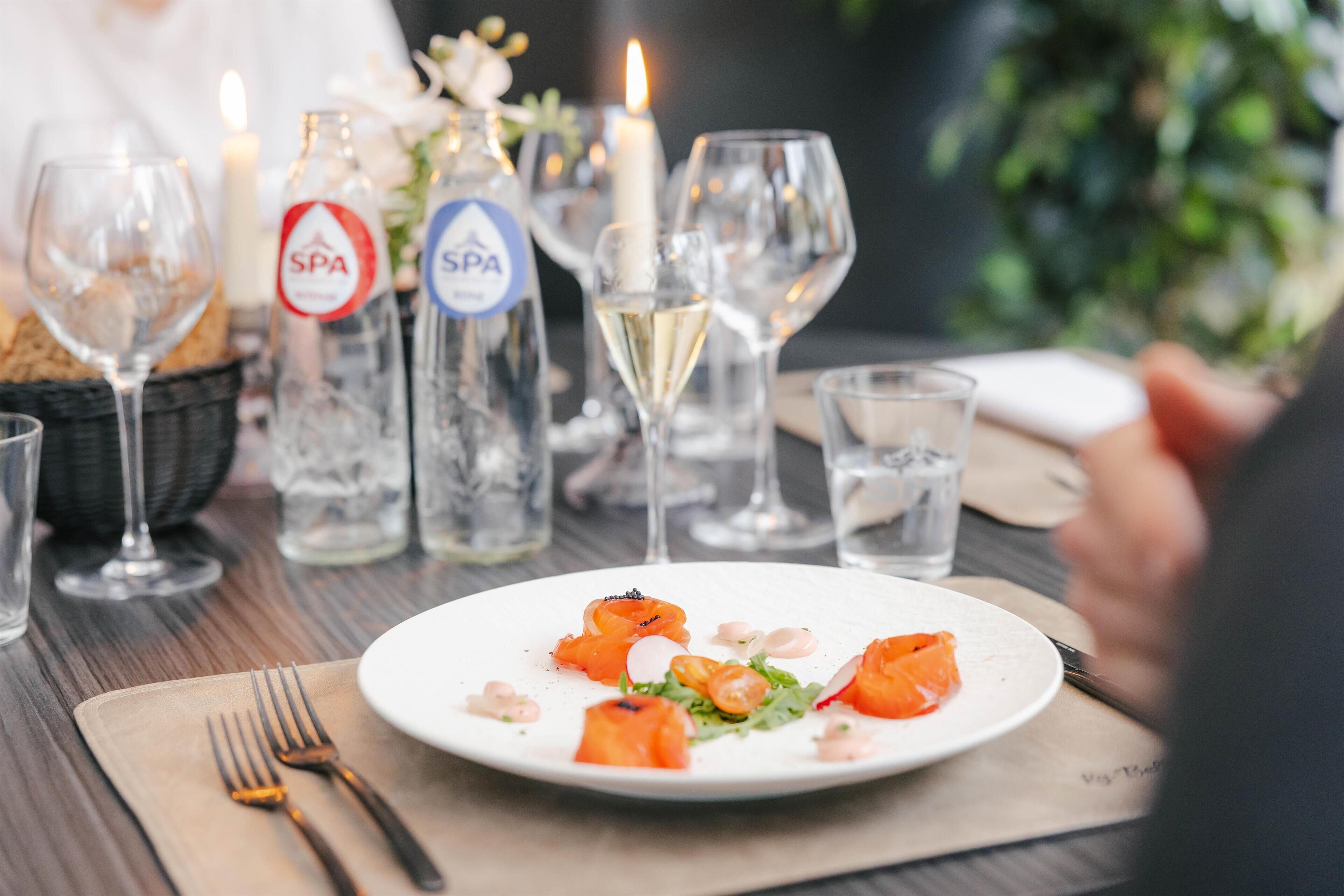 Una mesa de comedor con un plato de comida, vasos y botellas de agua.