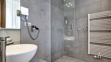 Een moderne badkamer met een grote witte wastafel, een douche met glazen wanden en een witte handdoekhouder.