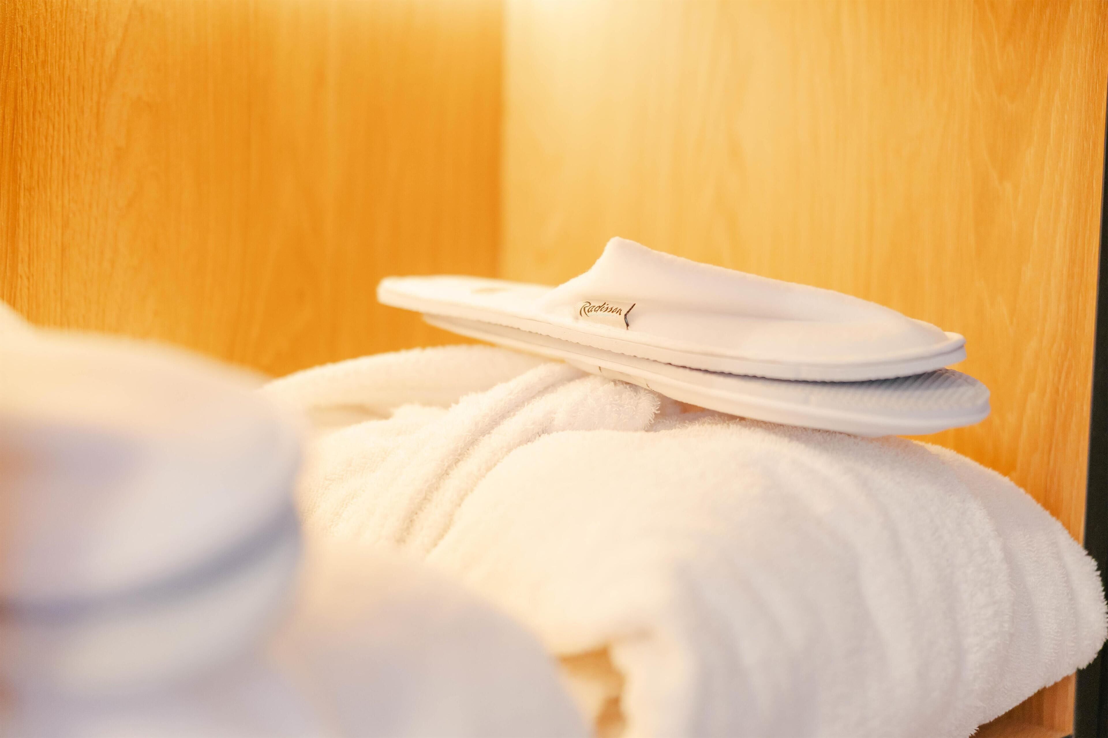 A white bathrobe and slippers on a wooden surface.