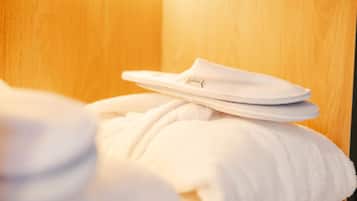 A white bathrobe and slippers on a wooden surface.