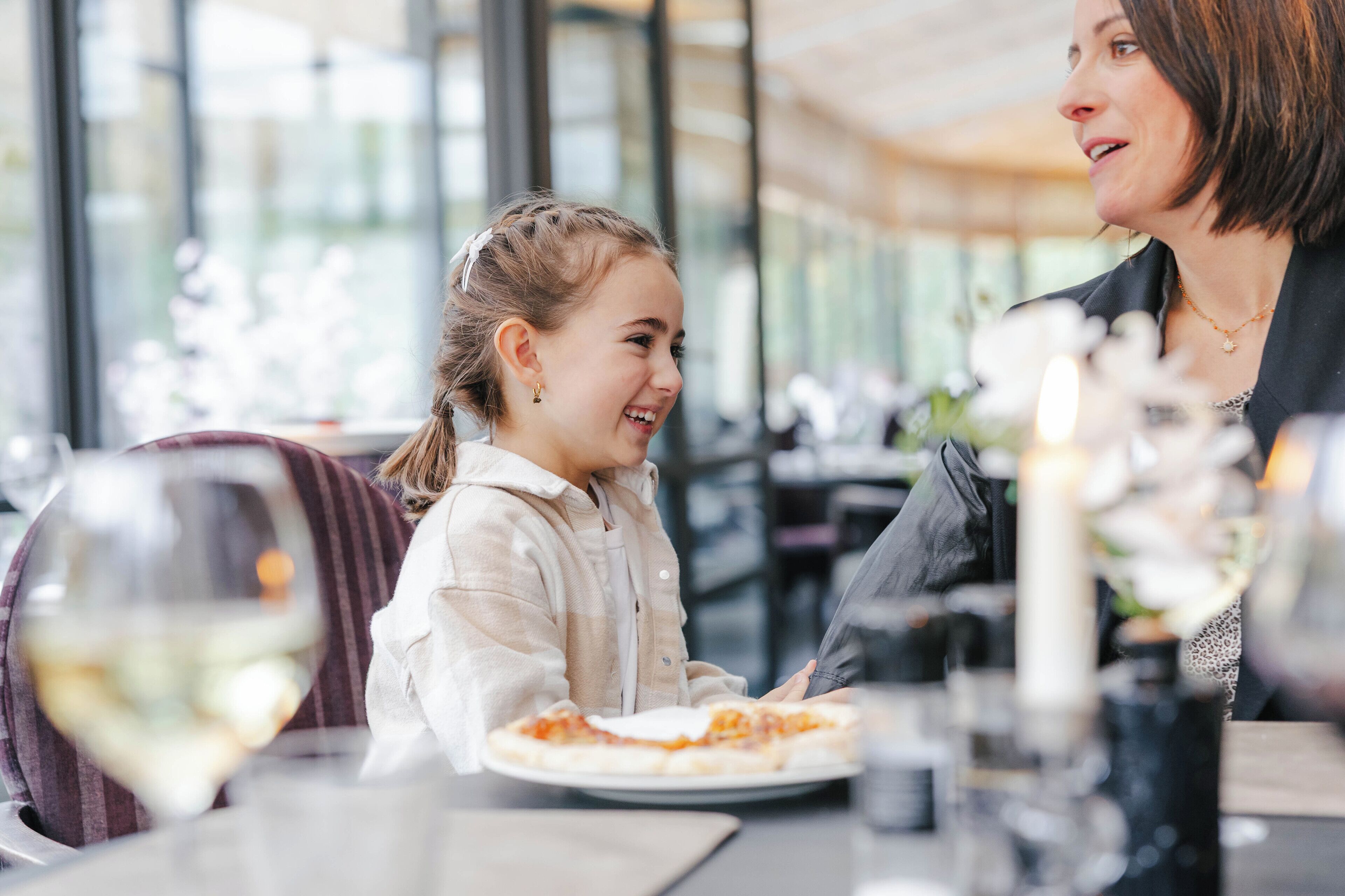 Un comedor con una mesa dispuesta para dos personas, que incluye un plato de comida y una copa de vino.