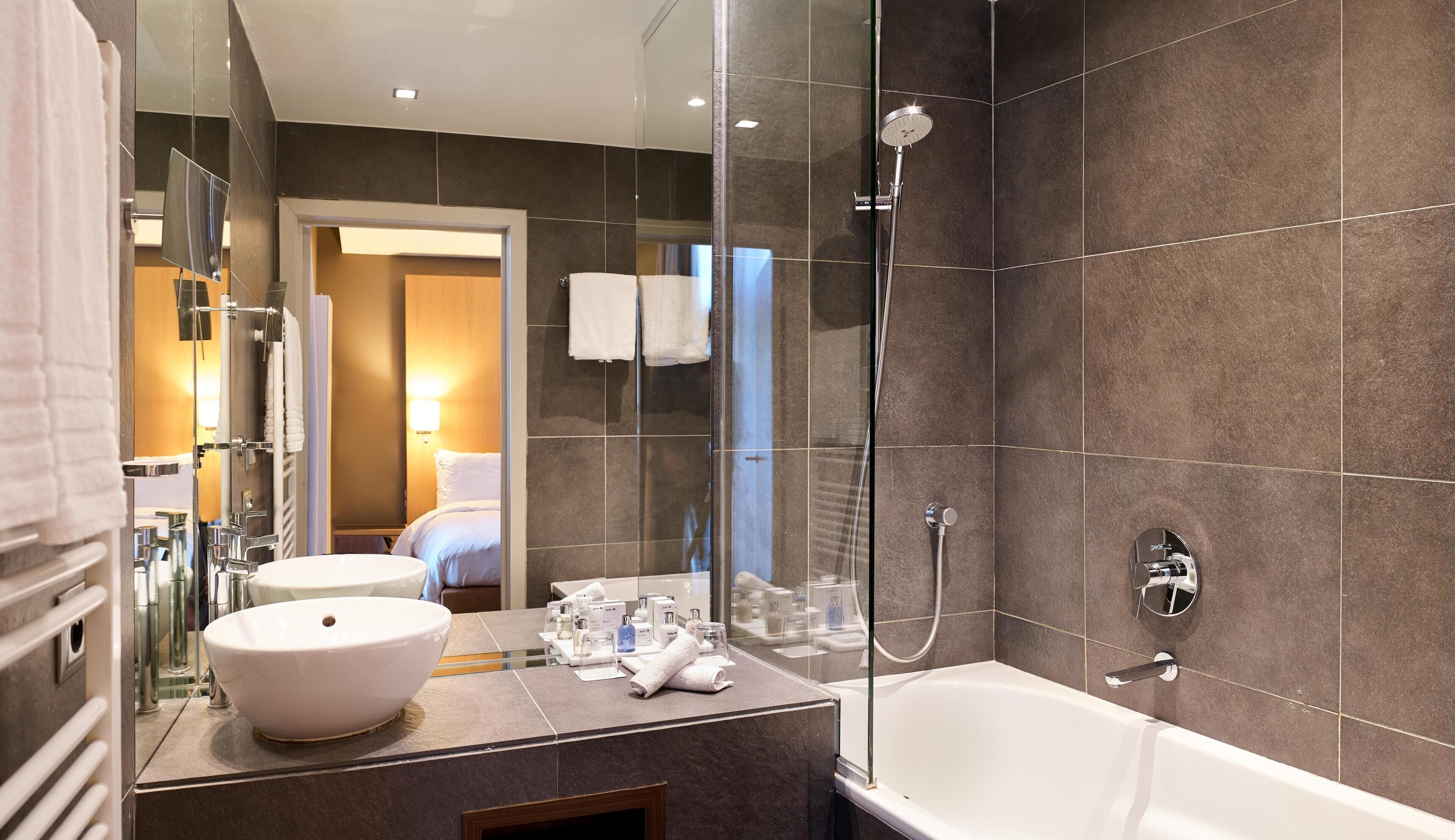 A modern bathroom with a large mirror, a white sink, a bathtub, and a shower.
