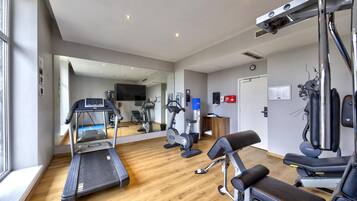 Een fitnessruimte met loopbanden, hometrainers en krachtapparaten.