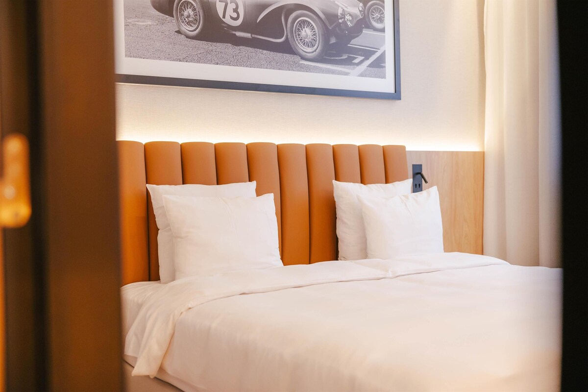 Una cama bien hecha con sábanas blancas y un cabecero naranja.