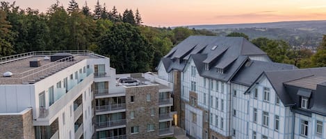 A multi-story building with balconies, a stone facade, and a rooftop terrace.