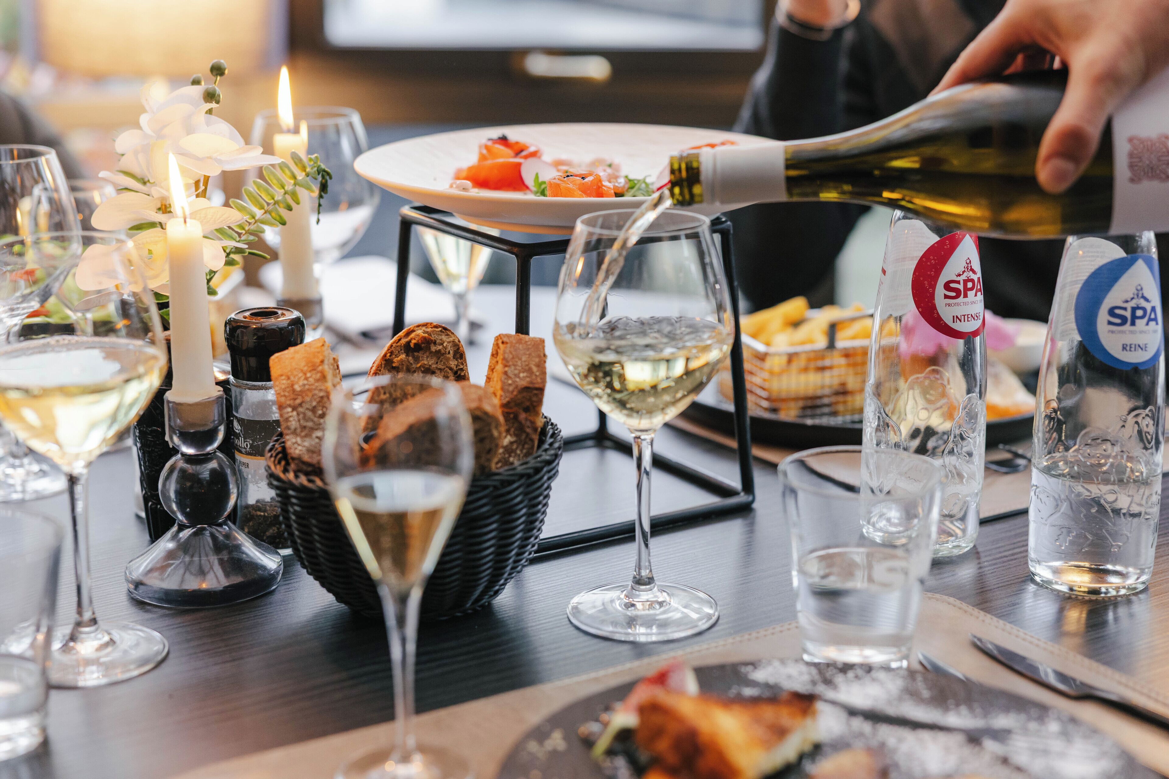 A dining table with various food items, glasses, and a bottle of wine.