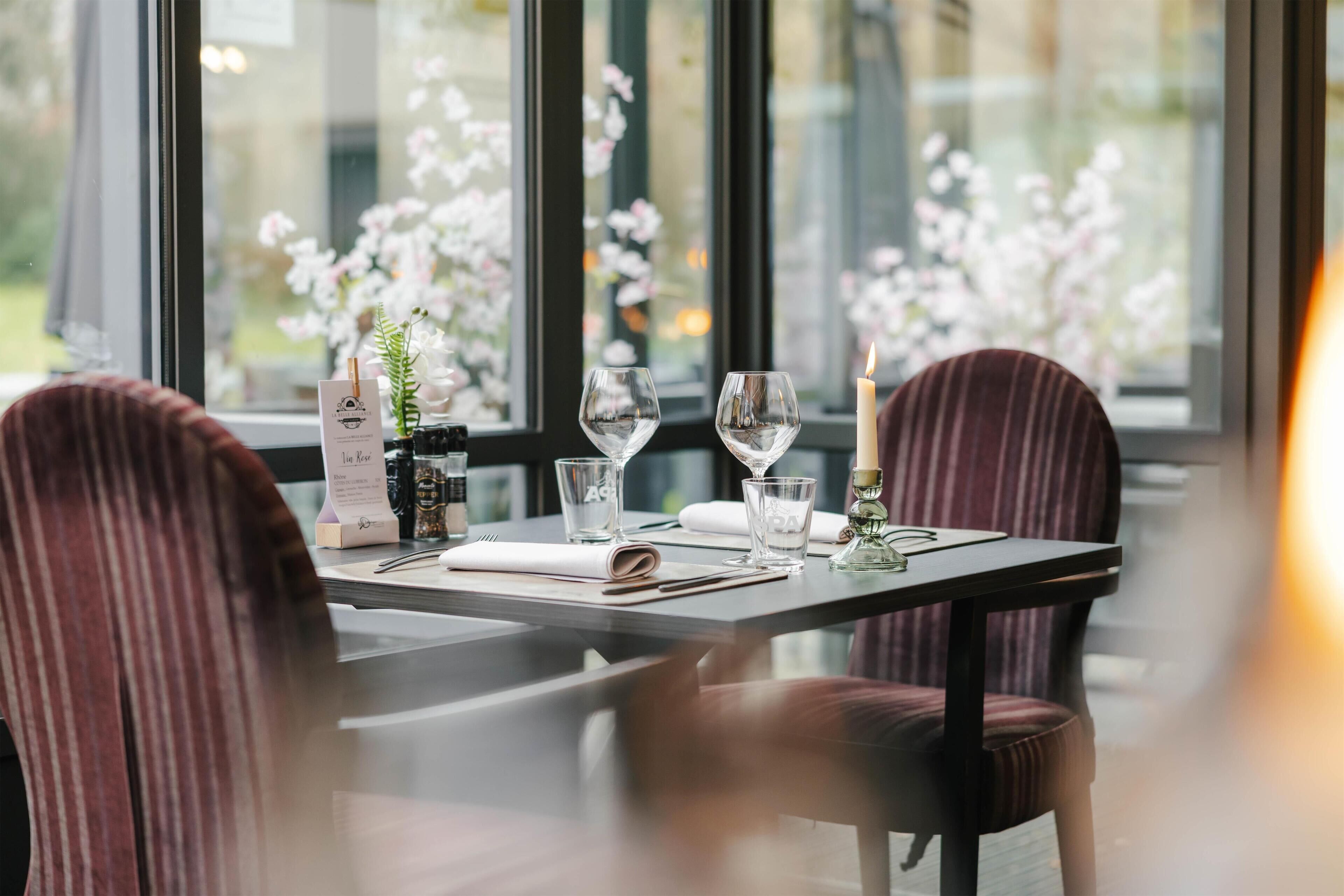 A dining table set with wine glasses, a candle, and a menu.