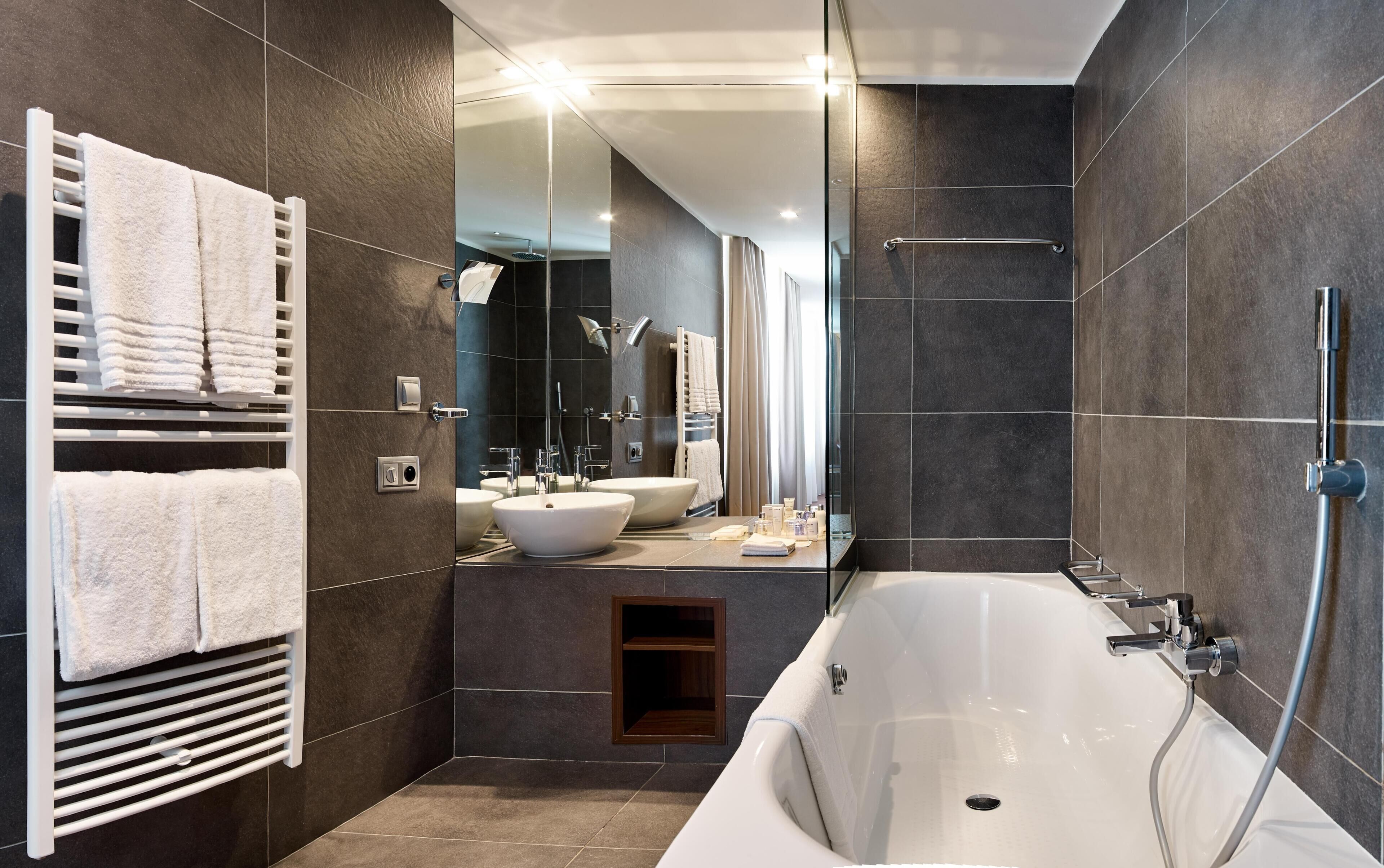 Un baño moderno con una bañera grande, un tocador doble y una ducha a ras de suelo.