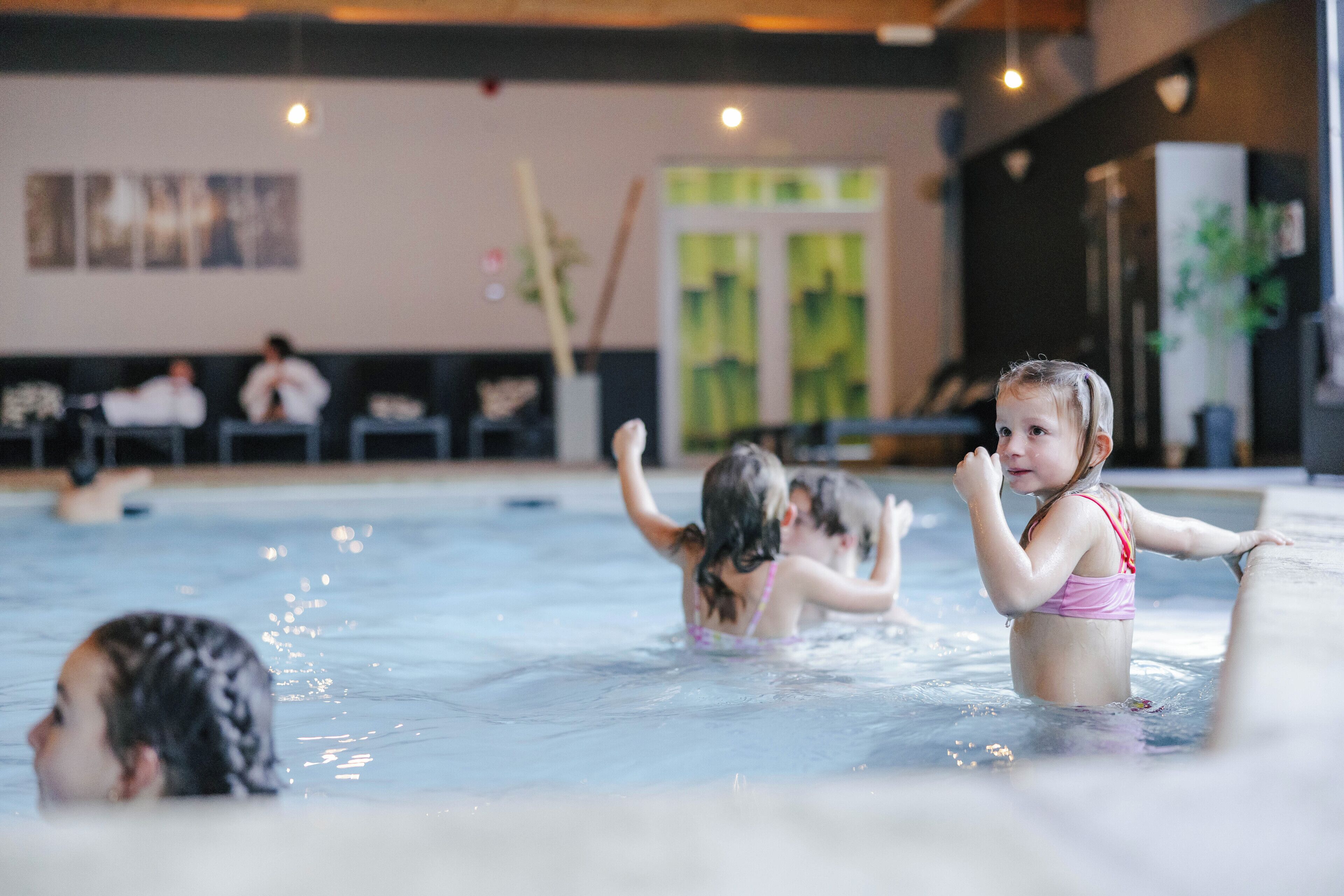 An indoor swimming pool with children playing.