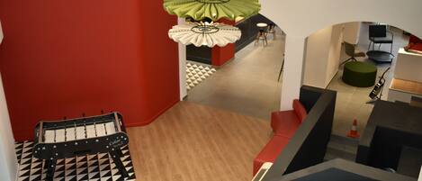 A modern interior with a checkered floor, a green hanging light fixture, and a red accent wall.