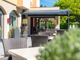 Un patio al aire libre con mobiliario de mimbre, una zona de estar cubierta y plantas en macetas.