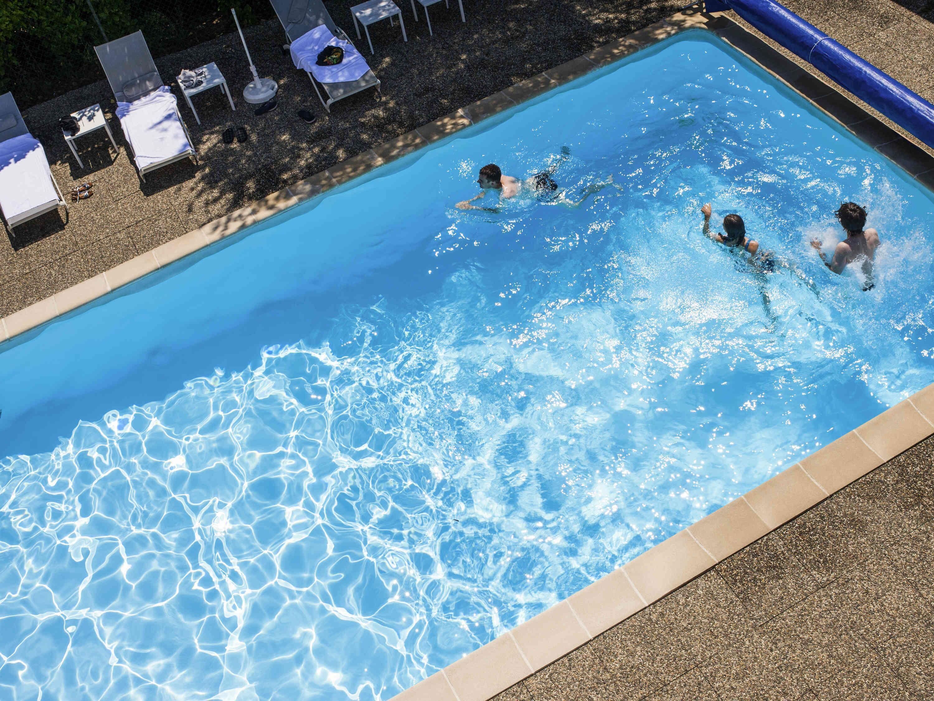 Una piscina al aire libre de temporada, sombrillas