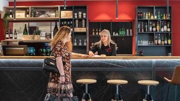 A bar area with a counter, stools, and shelves stocked with bottles.