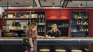A bar area with a counter, stools, and shelves stocked with bottles.