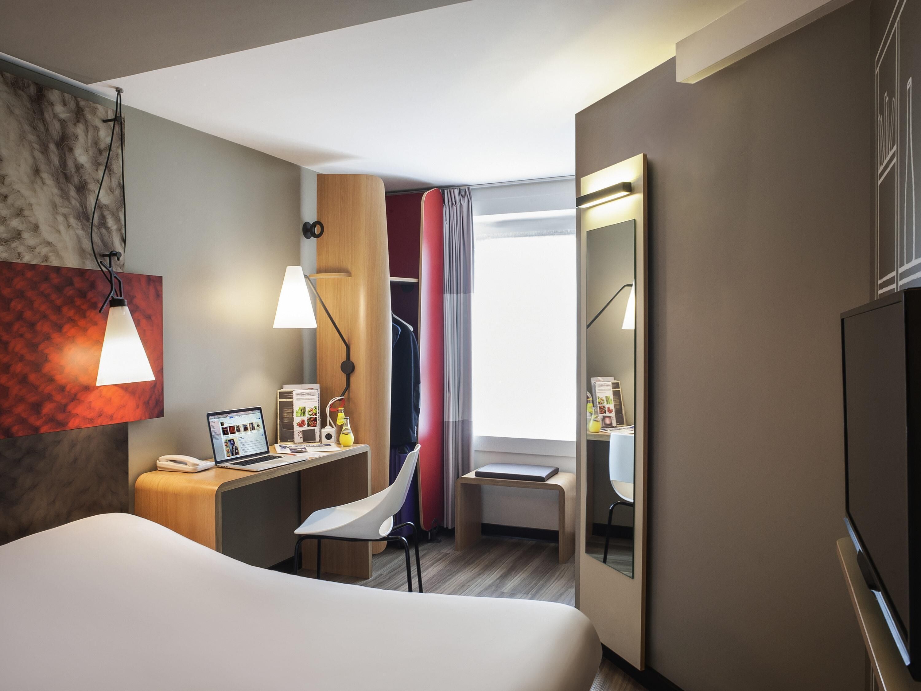 Una camera d'albergo moderna con un letto, una scrivania, una sedia e una televisione.