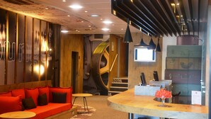Een modern interieur met een gebogen receptiebalie, een rode bank en een trap.
