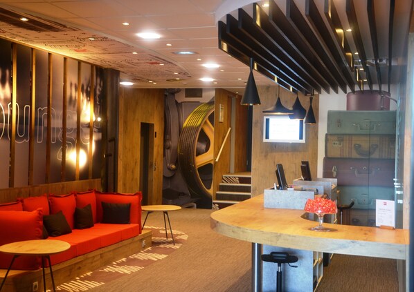 Un intérieur moderne avec un comptoir d’accueil incurvé, un canapé rouge et un escalier.