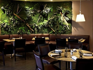 A restaurant with a green wall, brown leather seating, and wooden tables.