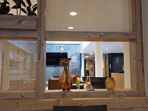 A hotel lobby with a wooden reception desk, a large screen TV, and a decorative vase. - Ibis Chalon Sur Saone Europe (Chalon-sur-Saone)