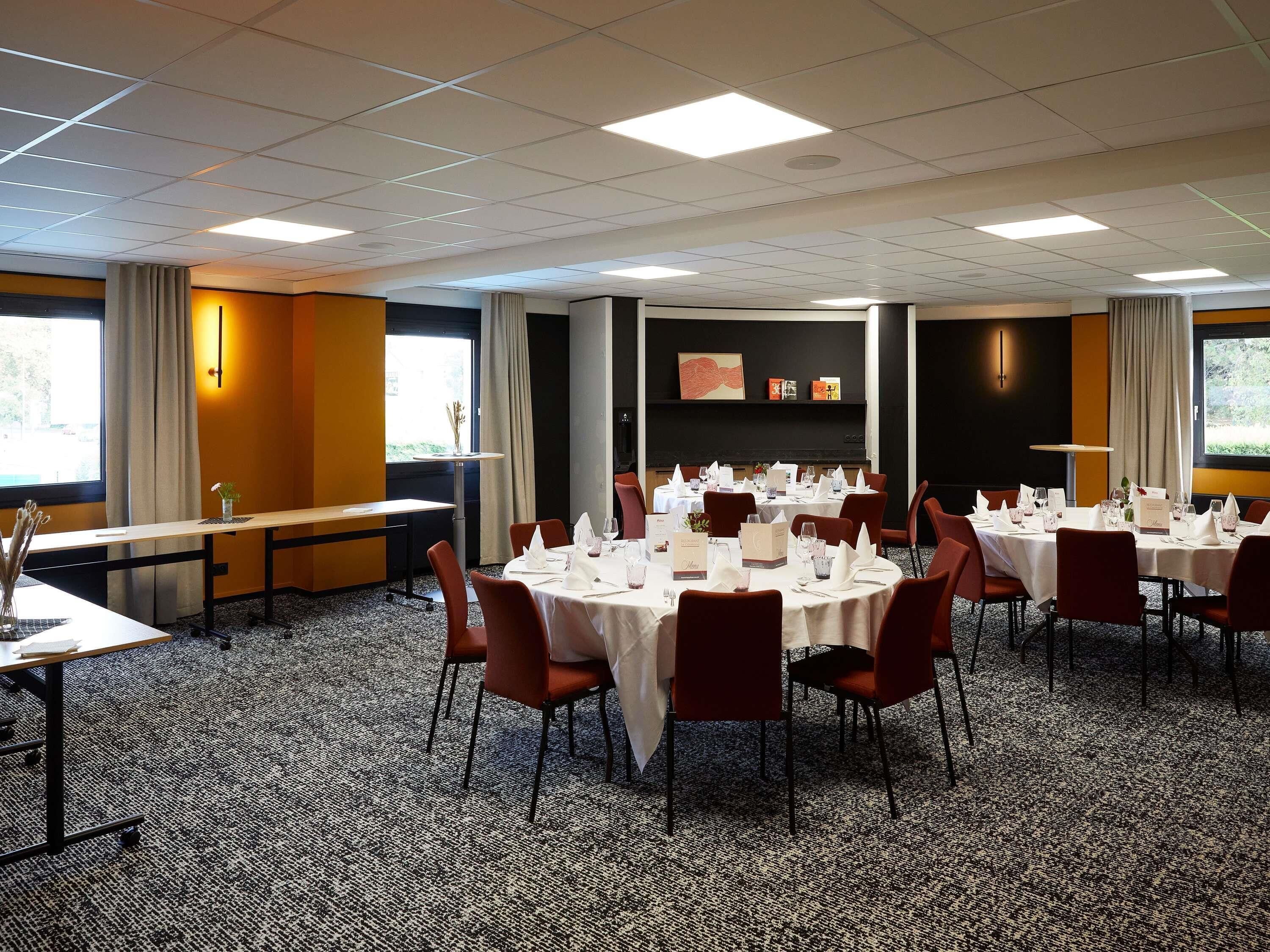A conference room with multiple tables set for dining, equipped with chairs, tablecloths, and centerpieces.