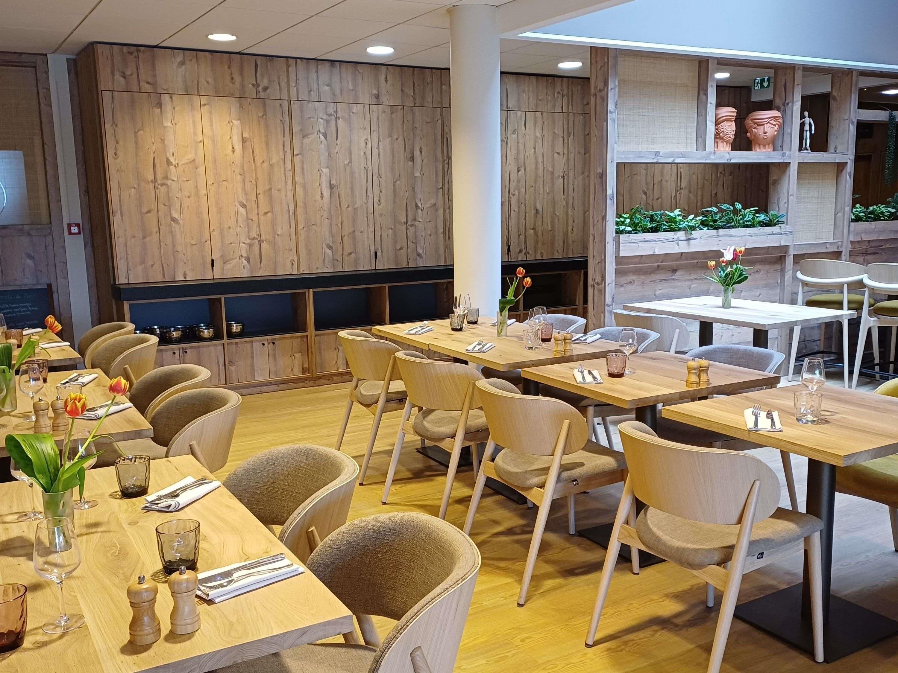 A restaurant interior with wooden panel walls, multiple dining tables, and chairs.