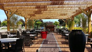 Een terras met rieten meubels, een rode plantenbak en een vloer met een patroon.