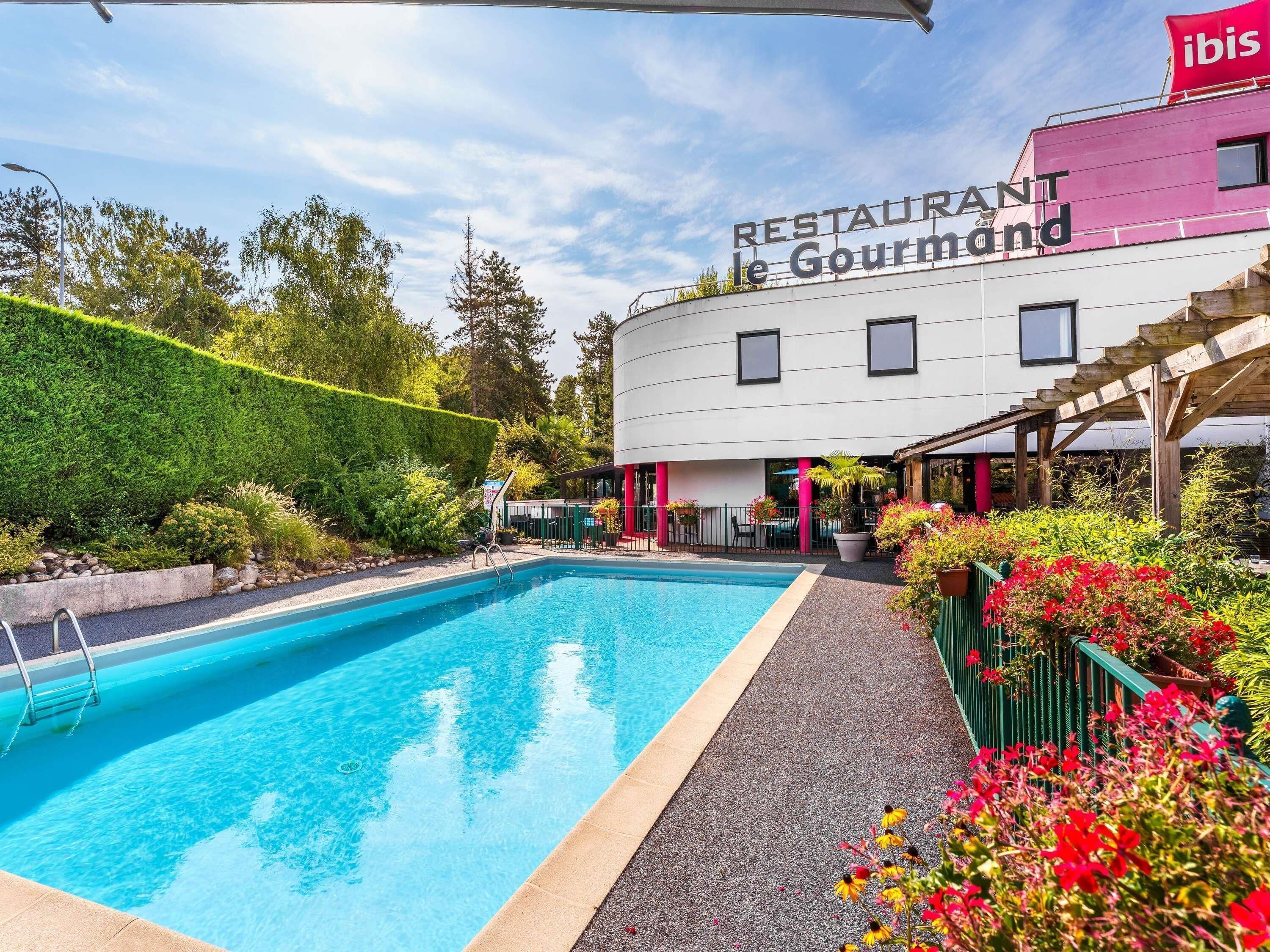 Une piscine jouxtant un bâtiment sur lequel est apposée une enseigne indiquant : « RESTAURANT le Gourmand ».