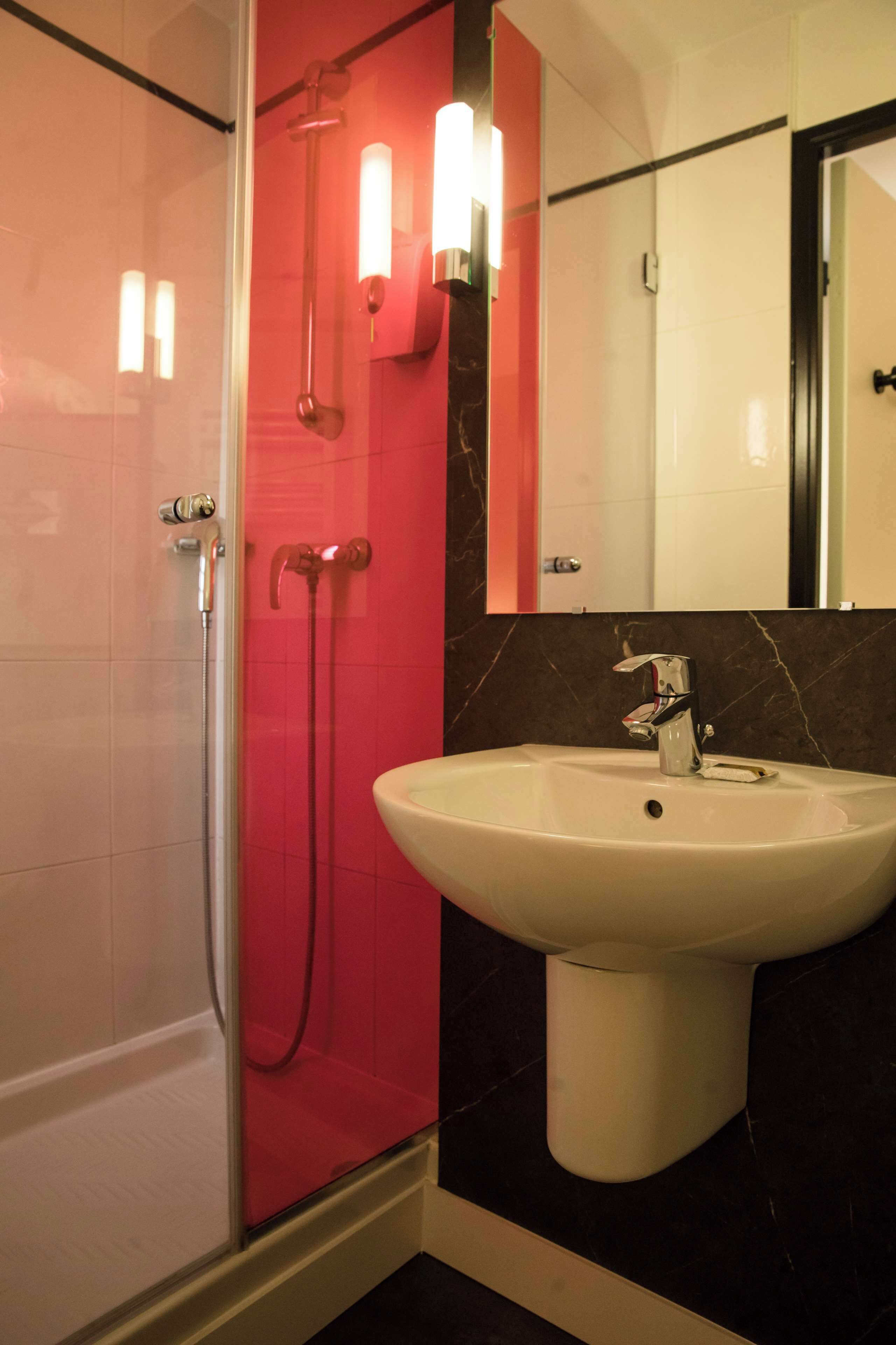 Un baño con ducha, lavamanos y espejo.