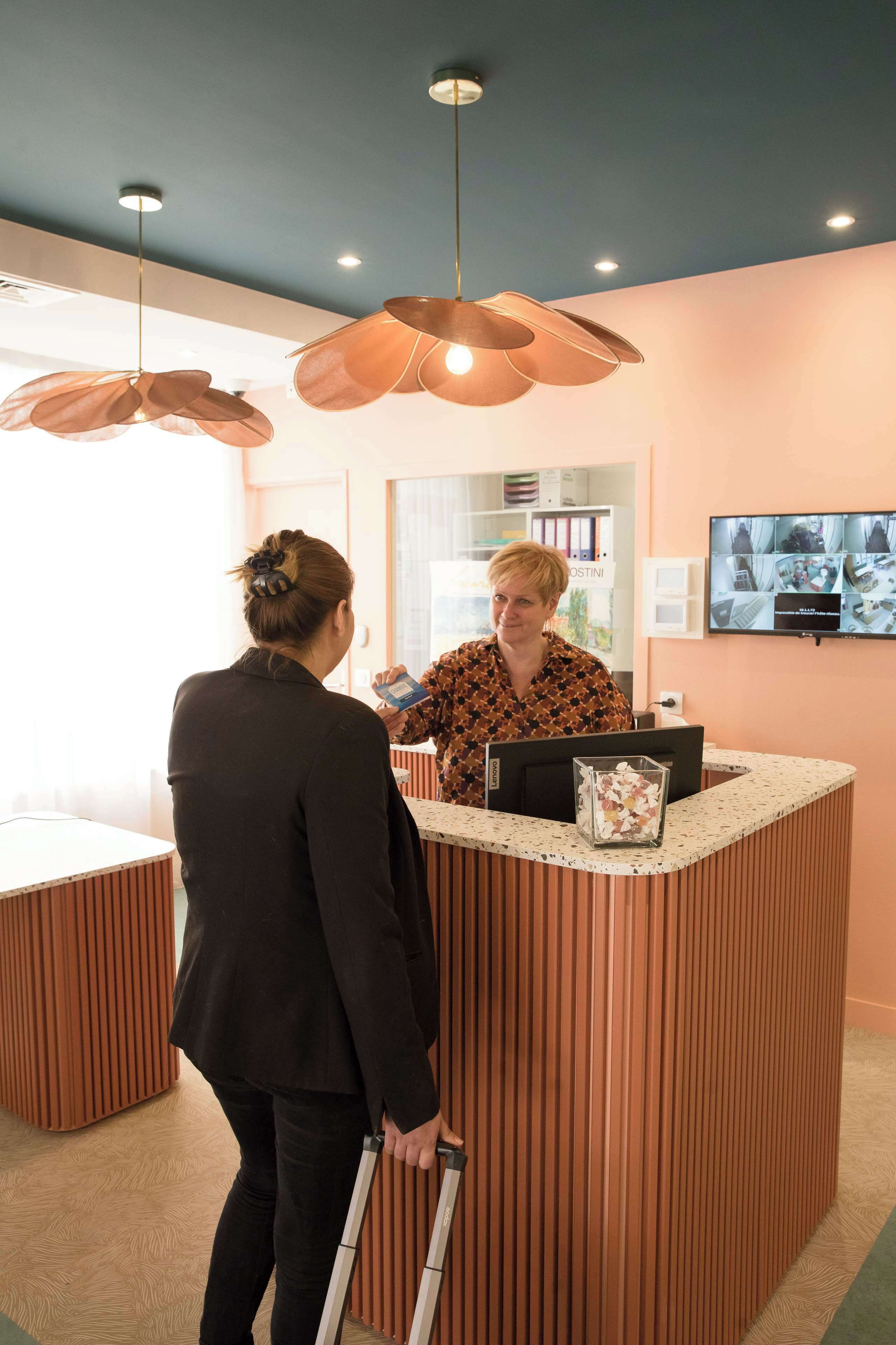 A reception area with a wooden reception desk, a computer, and a television displaying multiple screens.