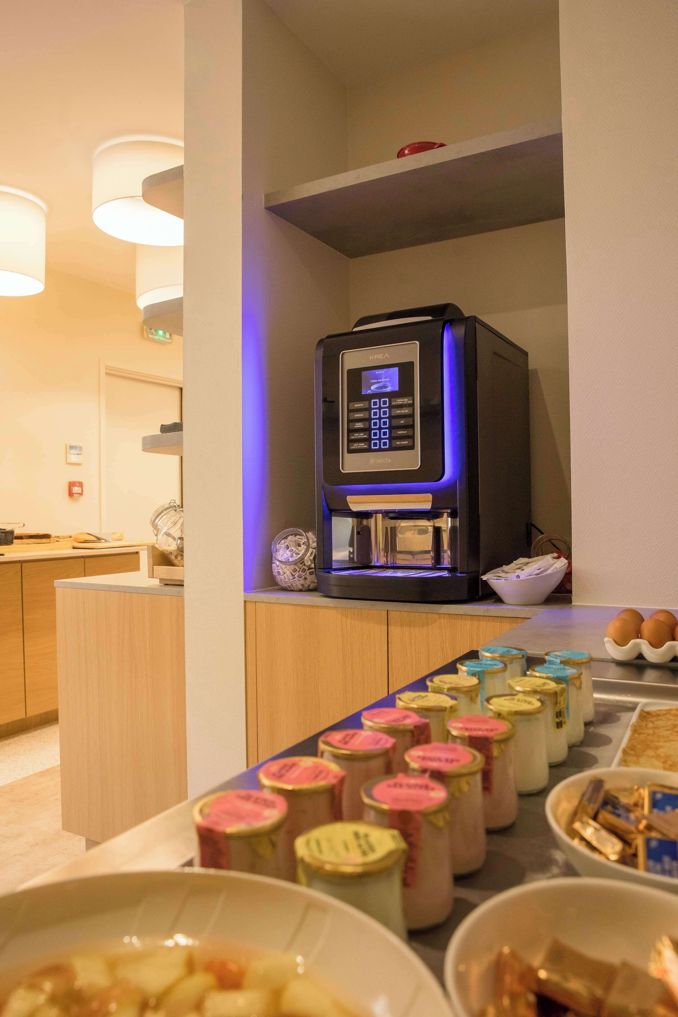 Una zona de cocina con cafetera, frascos de condimentos y un bol de huevos.