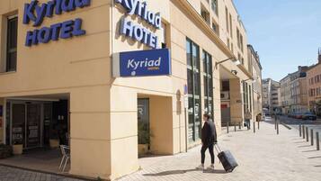 Un hotel llamado 'Kyriad Hotel' con una entrada despejada y señalización clara.