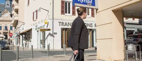 Una persona con maleta caminando frente a un hotel llamado 'Kyriad Hotel'.