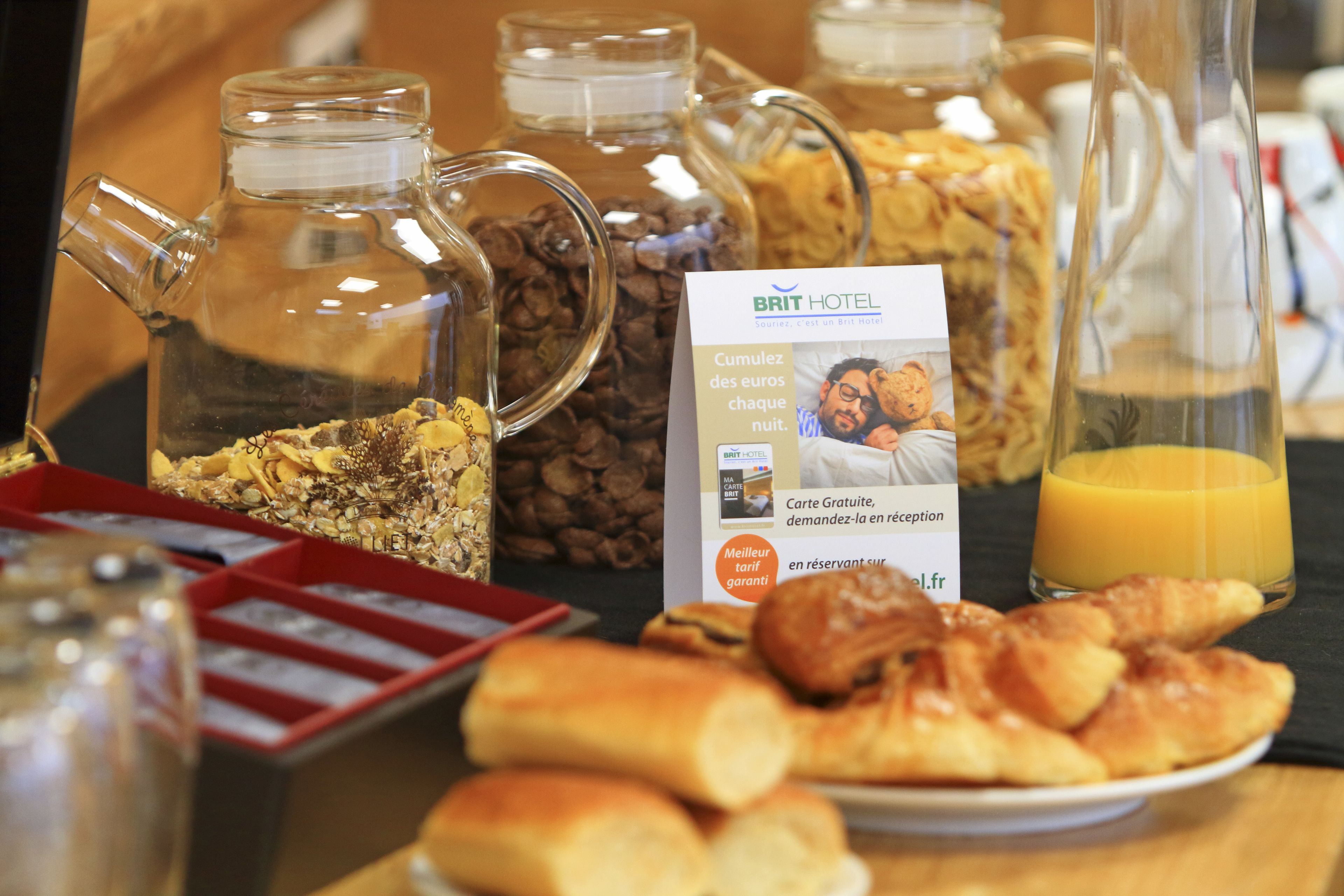 Un buffet de petit-déjeuner proposant une variété d’aliments, notamment des viennoiseries, des céréales et un verre de jus d’orange.