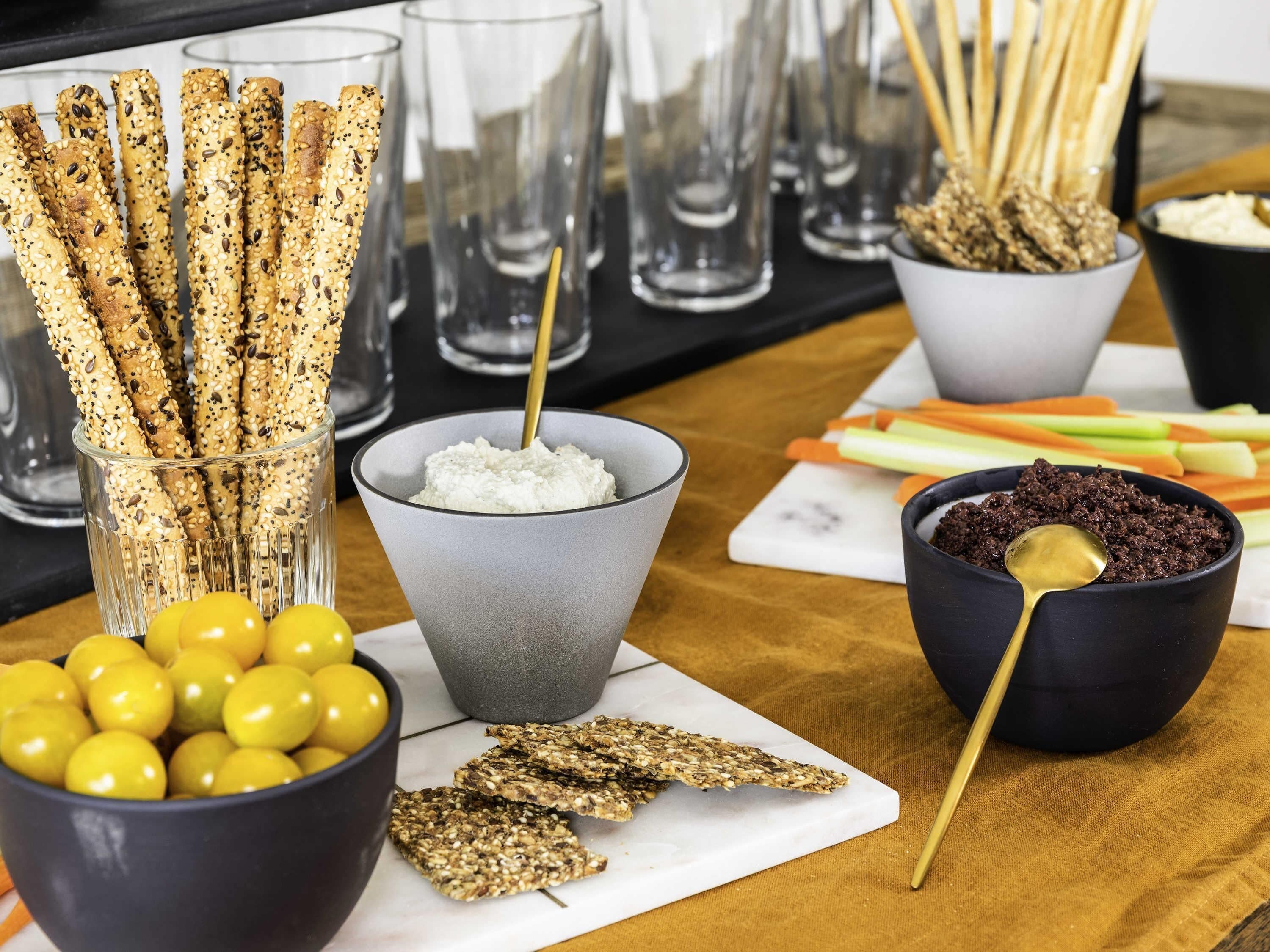 A table with various food items including breadsticks, olives, and bowls of dips.