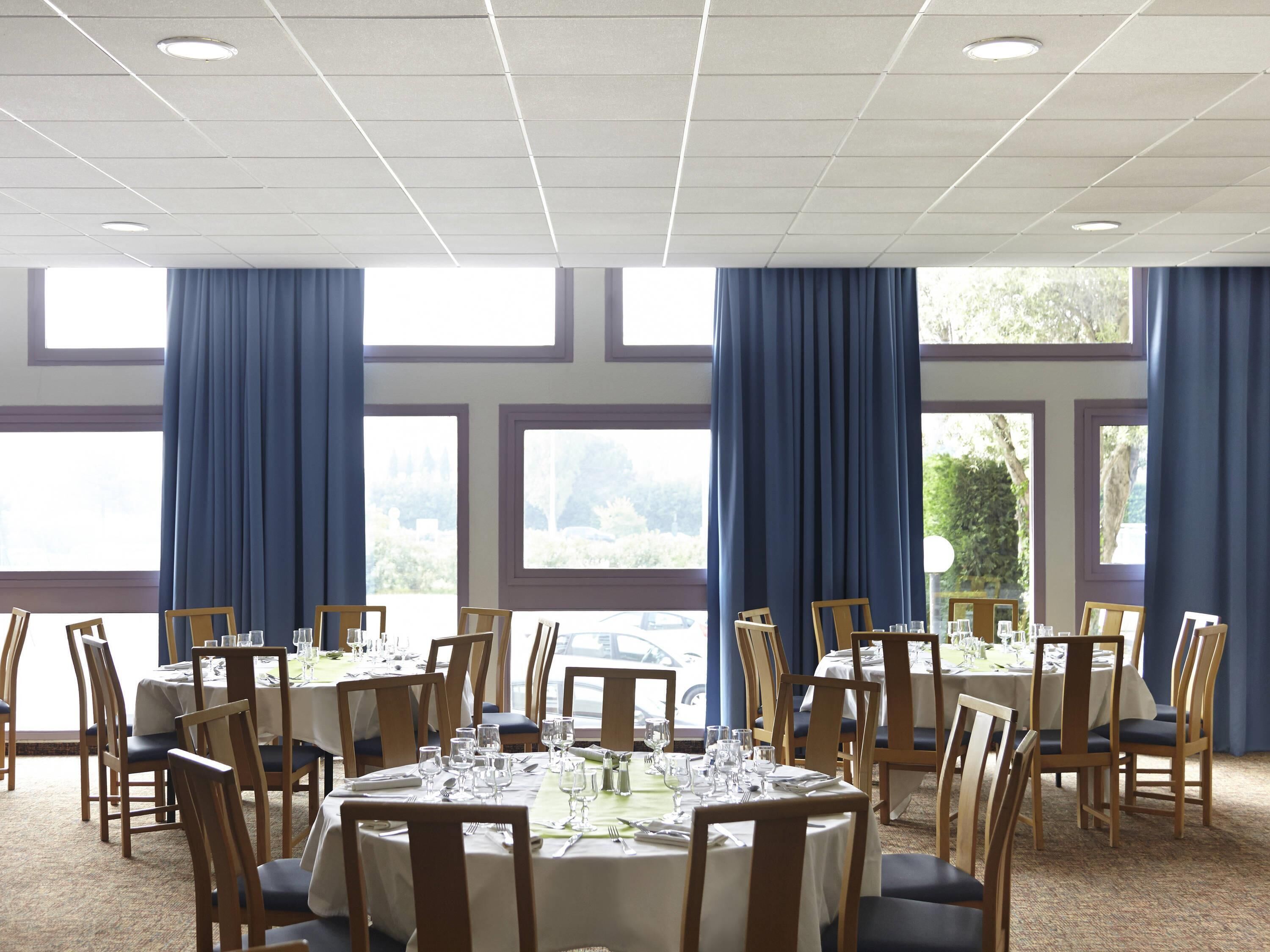 A dining area with round tables, chairs, and a carpeted floor.