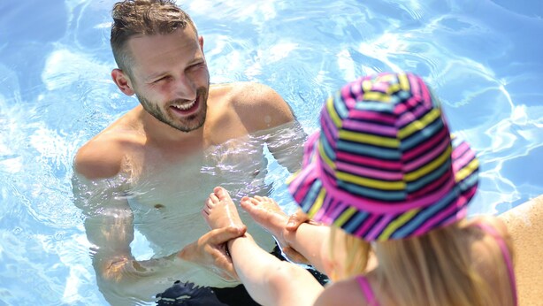 Una piscina con agua cristalina y borde de azulejos.