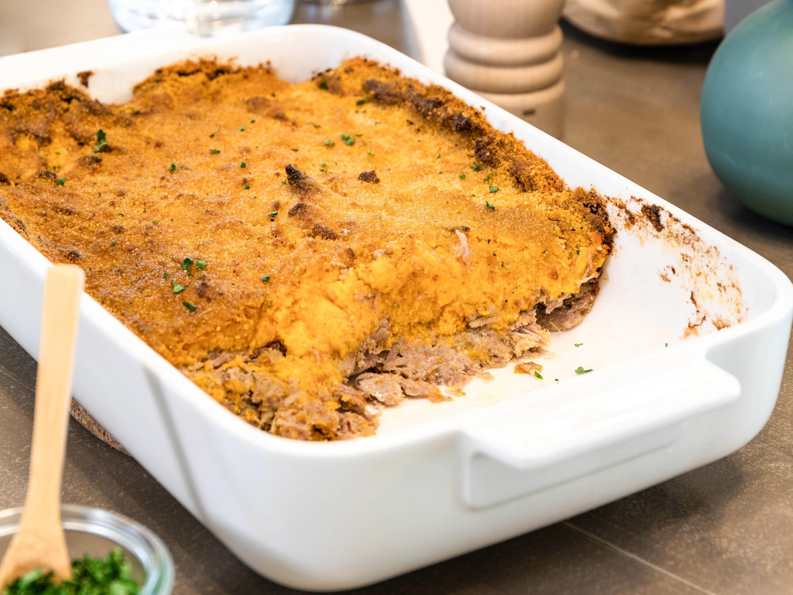 A white baking dish with a golden-brown crust on top, likely containing a baked dish.