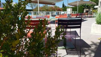 Una piscina al aire libre de temporada, sombrillas, tumbonas