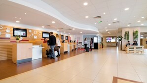 Un hall d’entrée spacieux, doté d’un comptoir de réception, de plusieurs écrans et d’un aménagement propre et moderne.