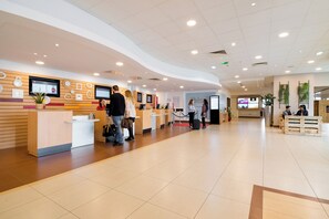 A spacious lobby with a reception desk, multiple screens, and a clean, modern design. - ibis Paris 17 Clichy-Batignolles (Paris)