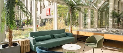 A modern indoor space with a green sofa, two chairs, a coffee table, and a model city display.