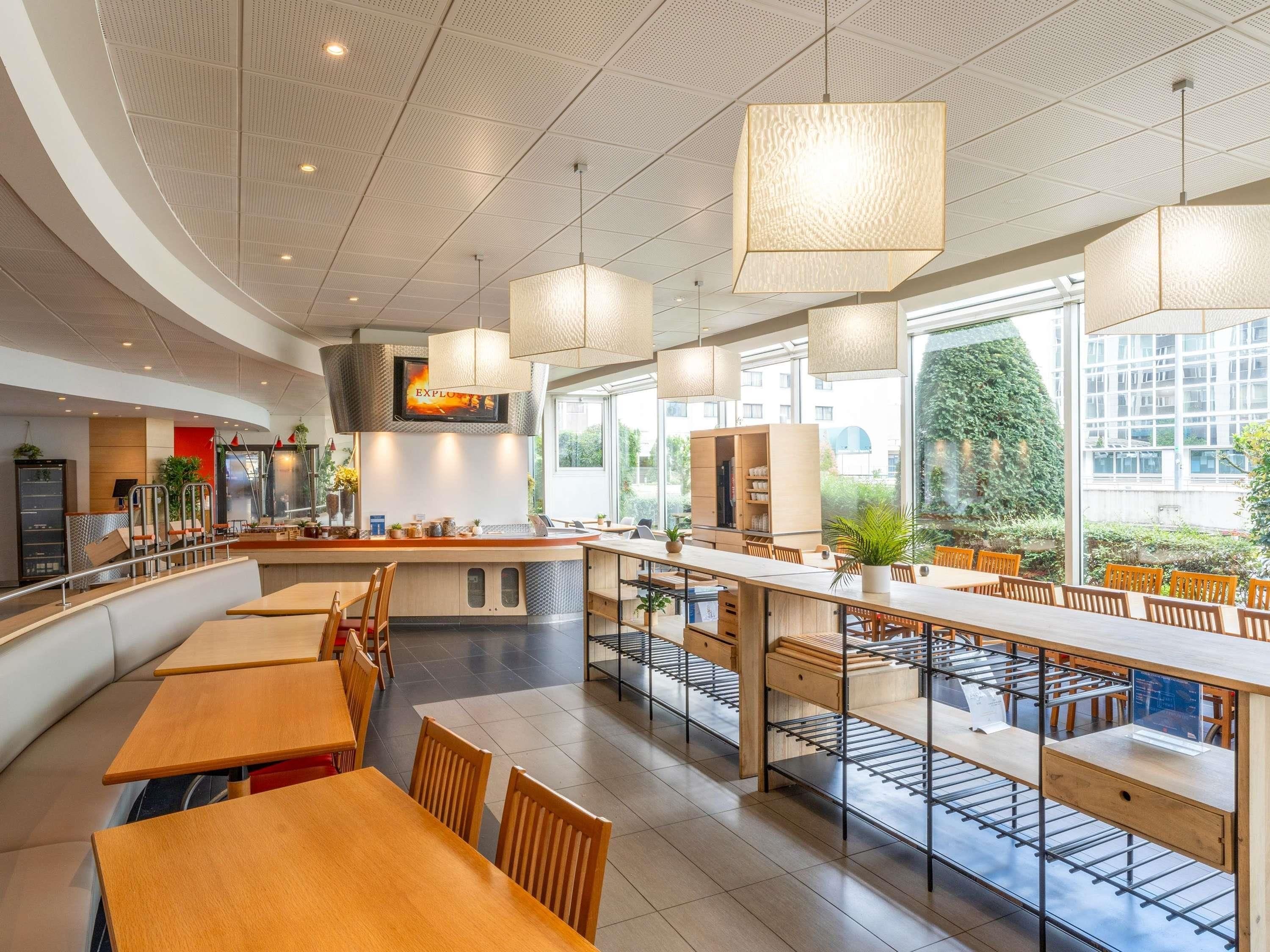 A modern restaurant with high ceilings, pendant lighting, and a central island.